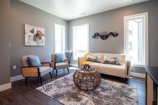 A living room with a white couch, two chairs, and a woven coffee table.