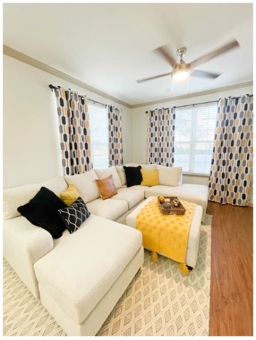 a living room with a white couch and a yellow ottoman