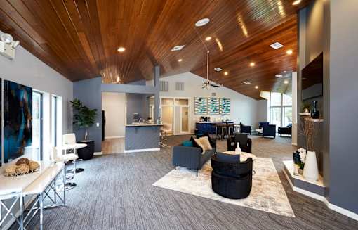 A modern living room with a wooden ceiling and grey carpet.