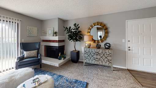 A living room with a fireplace, a chair, a mirror, and a plant.