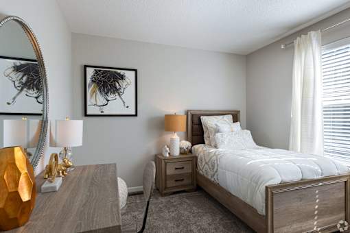 A bedroom with a large bed, a wooden nightstand, and a mirror on the wall.