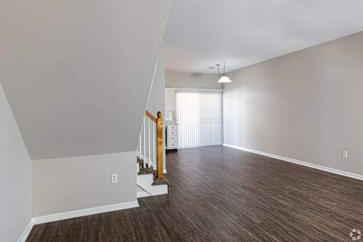 A room with wooden floors and a staircase with a wooden railing.