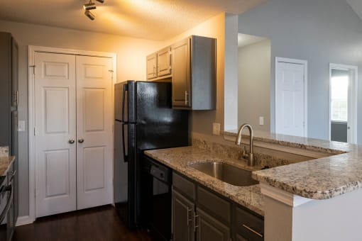 a kitchen with granite countertops and a black refrigerator