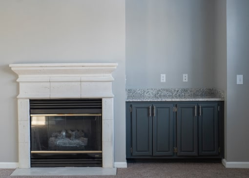 a fireplace with a mantel and a pair of cabinets next to it