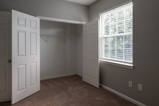 a bedroom with two windows and two closets
