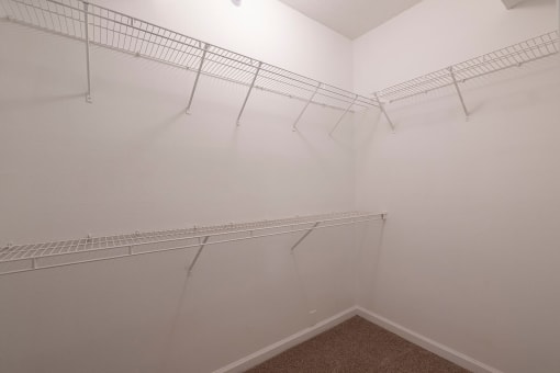 a walk in closet with white racks