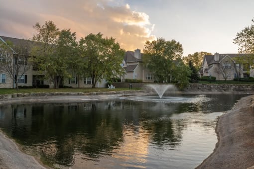 a pond with a fountain in front of a building