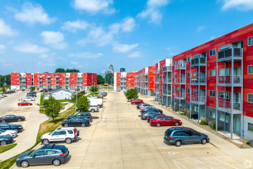 a row of red apartment buildings with cars parked in front of them