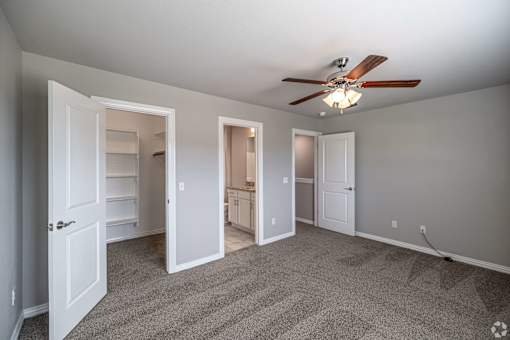 A room with a ceiling fan and carpeted floor.