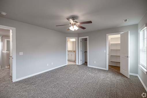 A spacious room with a ceiling fan and carpeted floor.