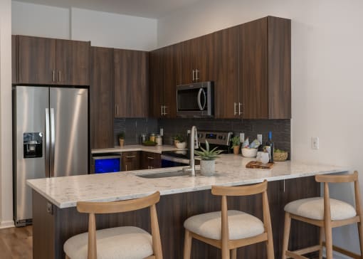 a kitchen with a marble counter top and three stools  at The Clearing at ONE28, Olathe, KS, 66062