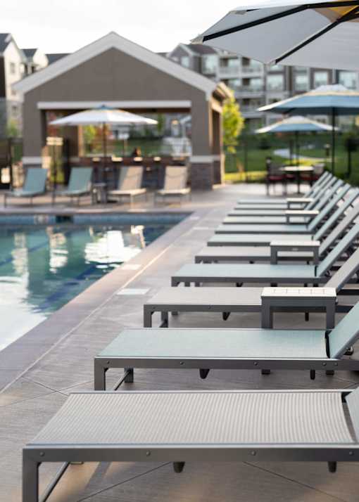 a row of lounge chairs next to a pool at The Clearing at ONE28, Olathe, 66062