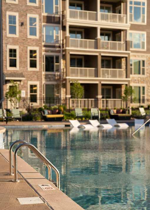 a swimming pool in front of an apartment building at The Clearing at ONE28, Olathe, Kansas