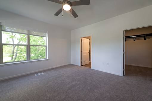 an empty living room with a large window and a ceiling fan at The Clearing at ONE28, Olathe