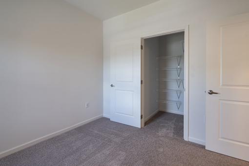 a room with white walls and a closet and a door to a closet at The Clearing at ONE28, Olathe, Kansas