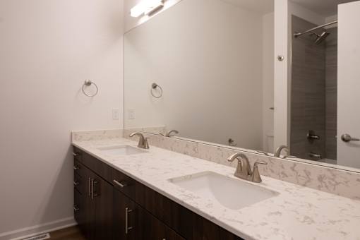 a bathroom with two sinks and a large mirror at The Clearing at ONE28, Olathe, KS
