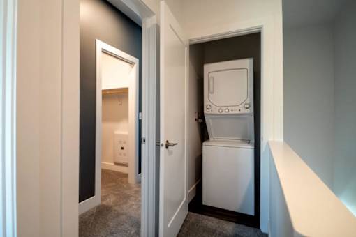 A white fridge is in a narrow hallway.