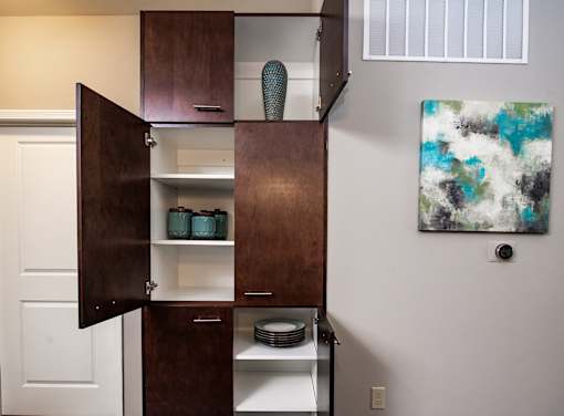 A brown cabinet with a white interior is open, revealing plates and bowls.
