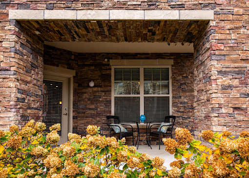 A patio with a table and chairs is framed by a brick wall.