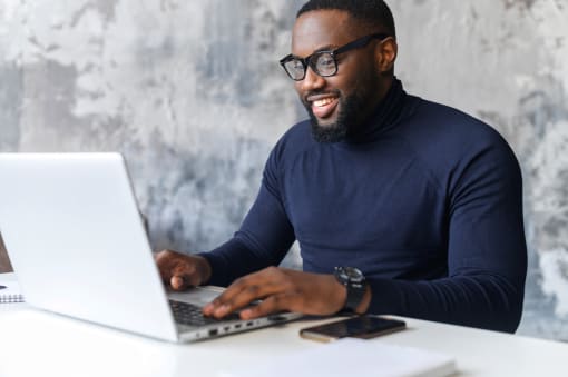 a man sitting at a table using a laptop computer at The Crest at South Point, McDonough, 30253