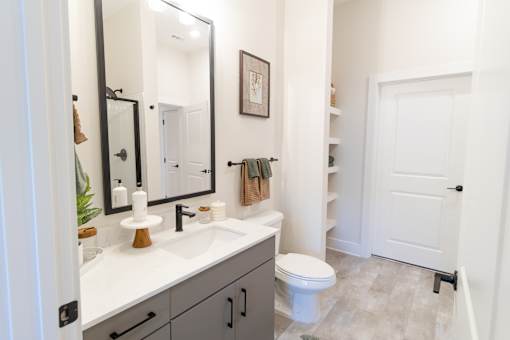 A bathroom with a toilet, sink, and mirror.