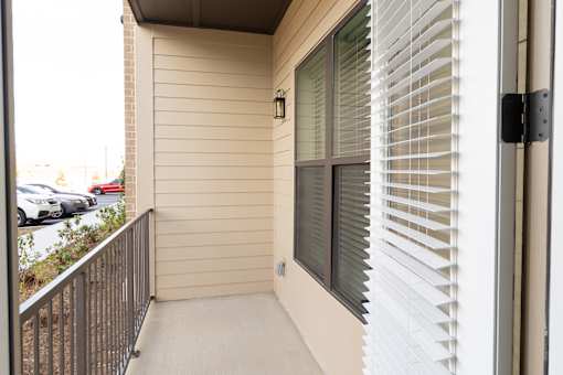 A balcony with a black railing and a window with white blinds.
