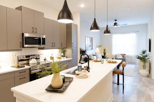 A modern kitchen with a white countertop and a black vase on it.