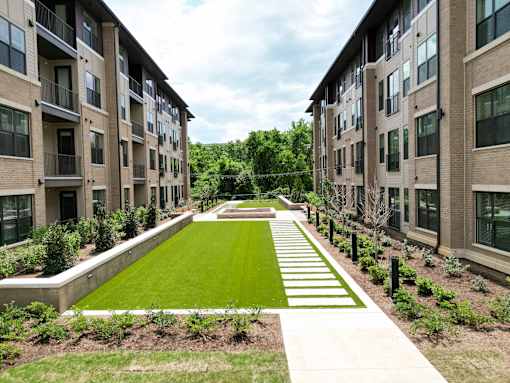 A long, narrow, grassy area separates two rows of apartment buildings.