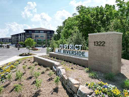 A sign that says District at Riverside stands in front of a building.