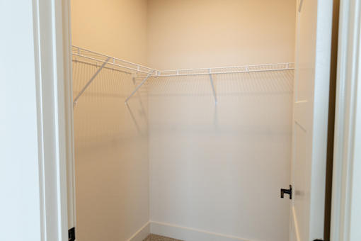 Compact cozy closet with white shelvesA white door is on the left of a dark brown wall.