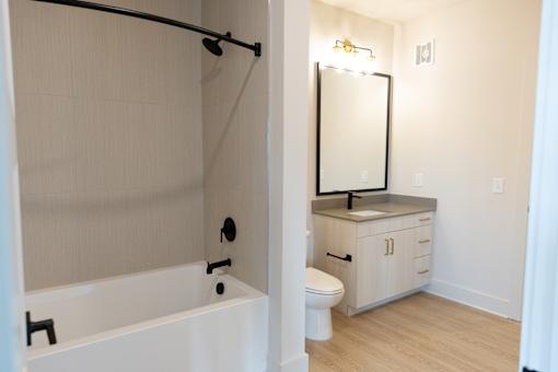 Bathtub in bathroom with wooden cabinet storage at District on the Etowah Apartments, Georgia