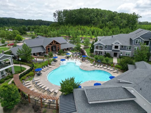 an aerial view of a resort style pool with lounge chairs and umbrellas at The Crest at Laurel Canyon Apartments, Canton, Georgia