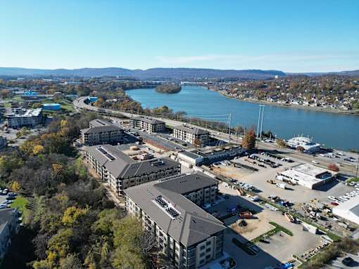 A large building complex sits in front of a body of water with a parking lot in front of it.at District at Riverside Apartments, Chattanooga