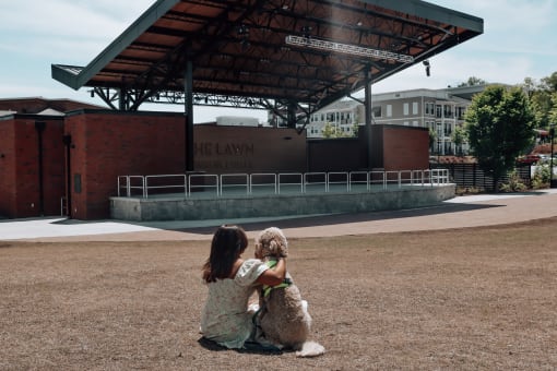 a girl and her dog sitting in front of a bandstand