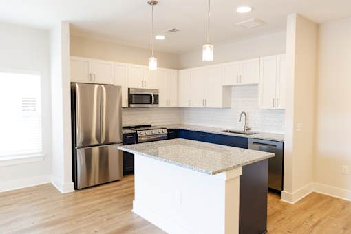 A kitchen with a refrigerator, microwave, oven, and sink.