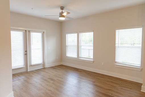 A room with a ceiling fan and three windows.