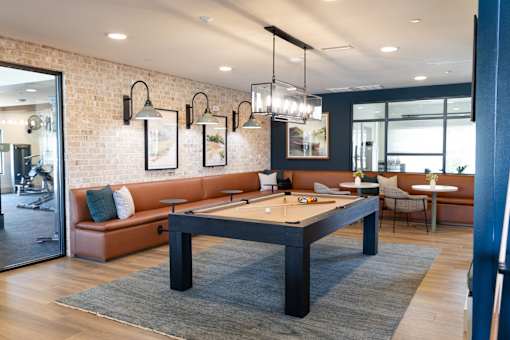 A billiard table is in the middle of a room with a brick wall and a mirror.