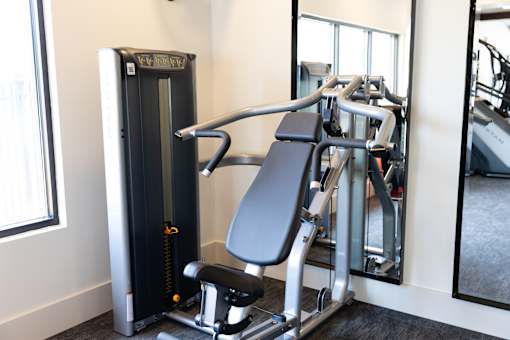 A gym with a weight machine and a mirror.