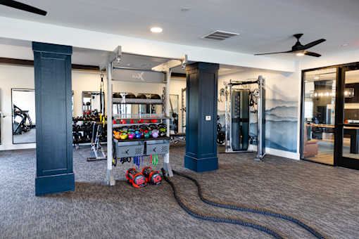 A gym with a variety of equipment including a treadmill, weights, and a rowing machine.