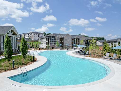 A large outdoor swimming pool surrounded by lounge chairs and umbrellas.