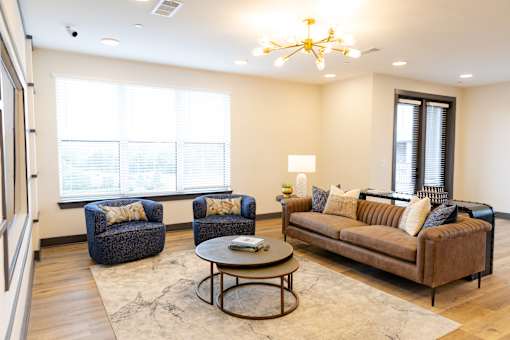 A living room with a brown couch, two chairs, and a coffee table.