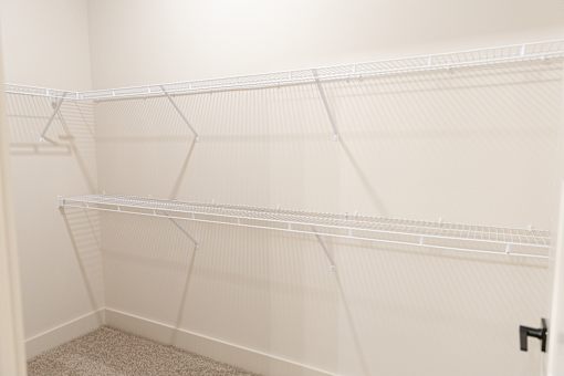 Soothing calm closet with white shelves at District on the Etowah Apartments, Canton, GA 30114