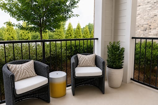 Covered balcony with wicker seating and greenery at The Crest at Acworth Apartments, Georgia, 30102