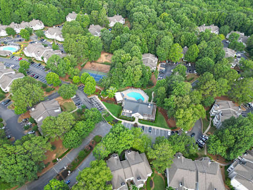 A bird's eye view of a residential area with houses, trees, and a swimming pool.