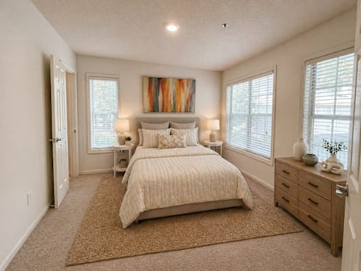 A bedroom with a large bed, a dresser, and a painting on the wall.
