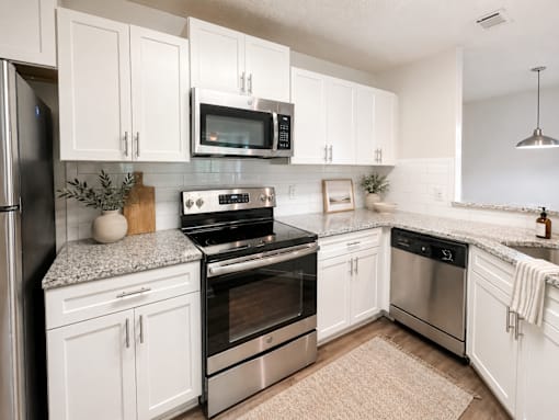 A kitchen with white cabinets and stainless steel appliances.
