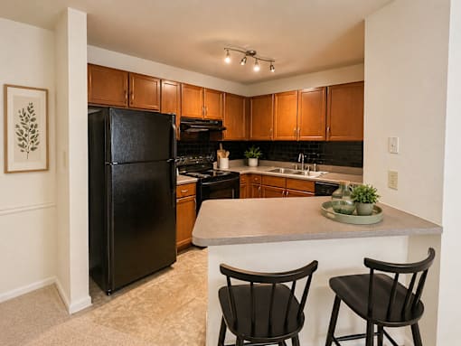 A kitchen with black chairs and a black refrigerator.
