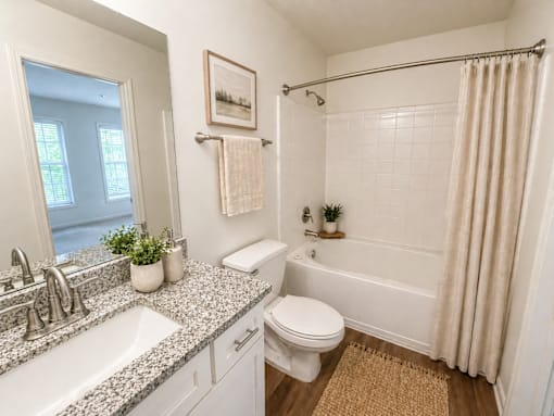 A bathroom with a white toilet, a sink, a bathtub, and a shower.