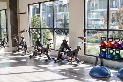a gym with exercise bikes and weights in front of a window at The Crest at Laurel Canyon Apartments, Georgia