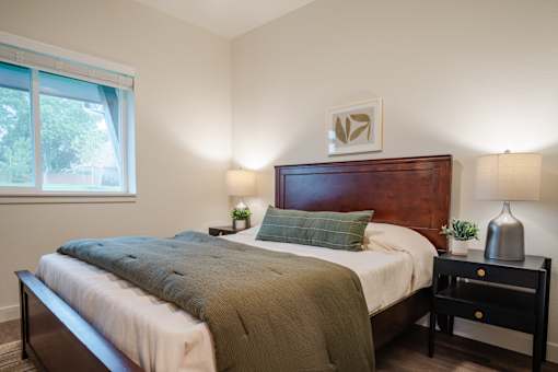 A bedroom with a bed, nightstand, and lamp.